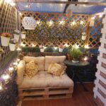 Terraza chillout con celosías y seto artificial de hiedra. Decorado con luces
