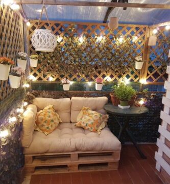 Terraza chillout con celosías y seto artificial de hiedra. Decorado con luces