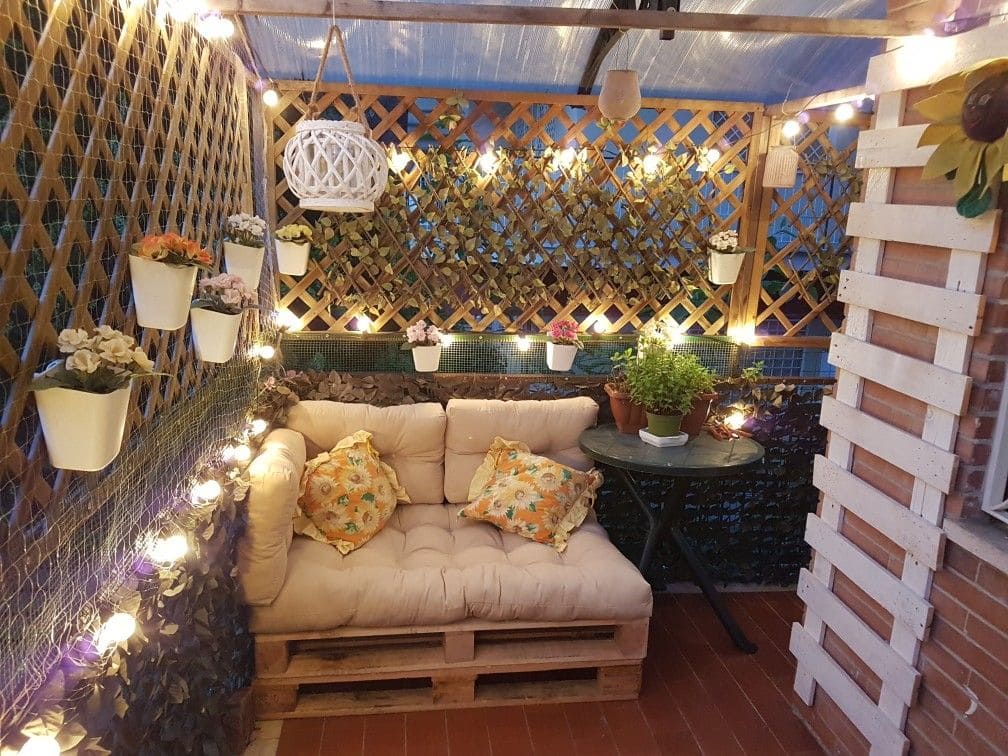 Terraza chillout con celosías y seto artificial de hiedra. Decorado con luces